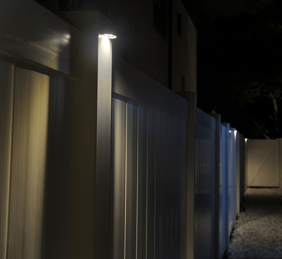 Illuminated fence at night with soft lighting highlighting metal panels.