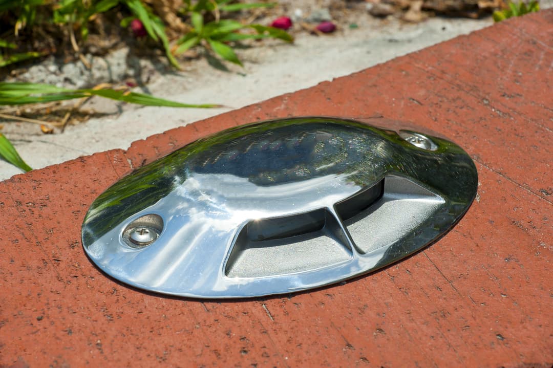 Chrome footstep ramp embedded in brick surface, surrounded by greenery.